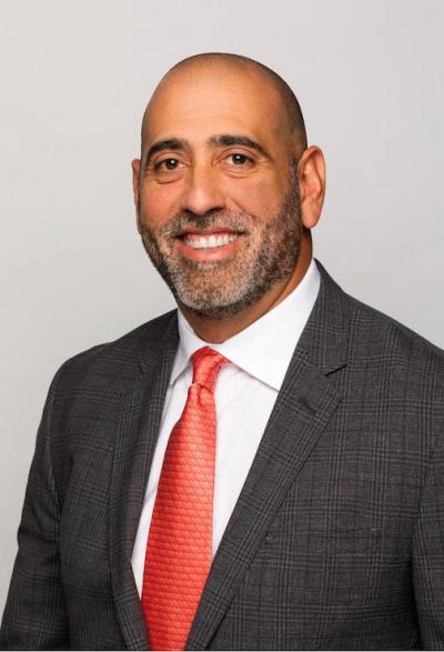 a headshot of a man wearing a suit and a red tie.