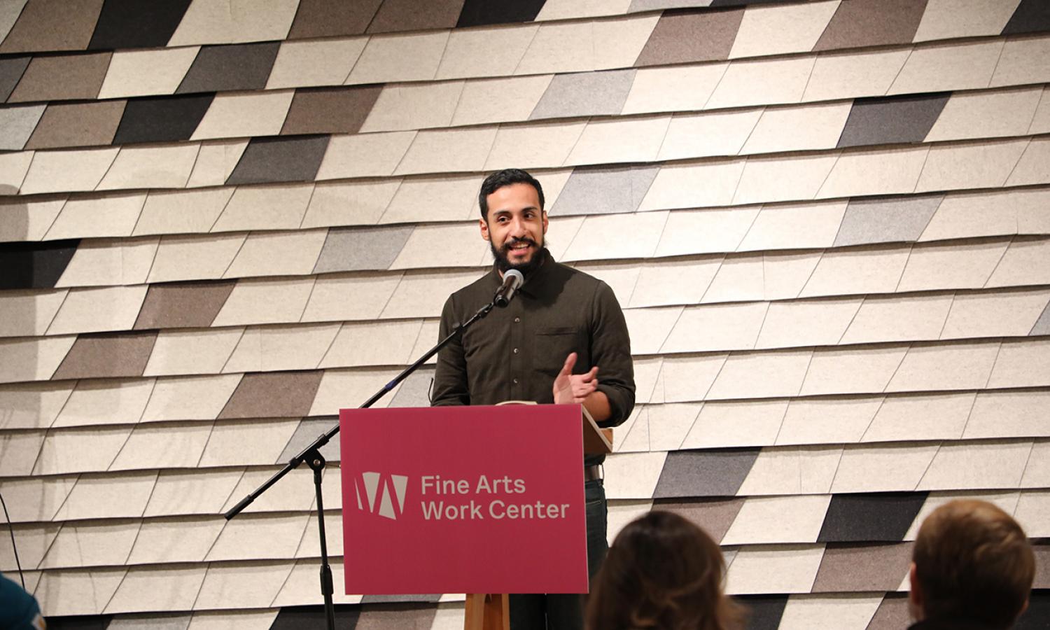 Writing Fellow, Eduardo Martinez-Leyva, reading at a podium in the Stanley Kunitz Common Room at the Fine Arts Work Center