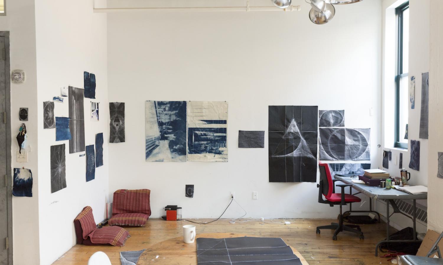 Wide view of a room with blue artworks on the wall. Photographer: Brad Ogbonna