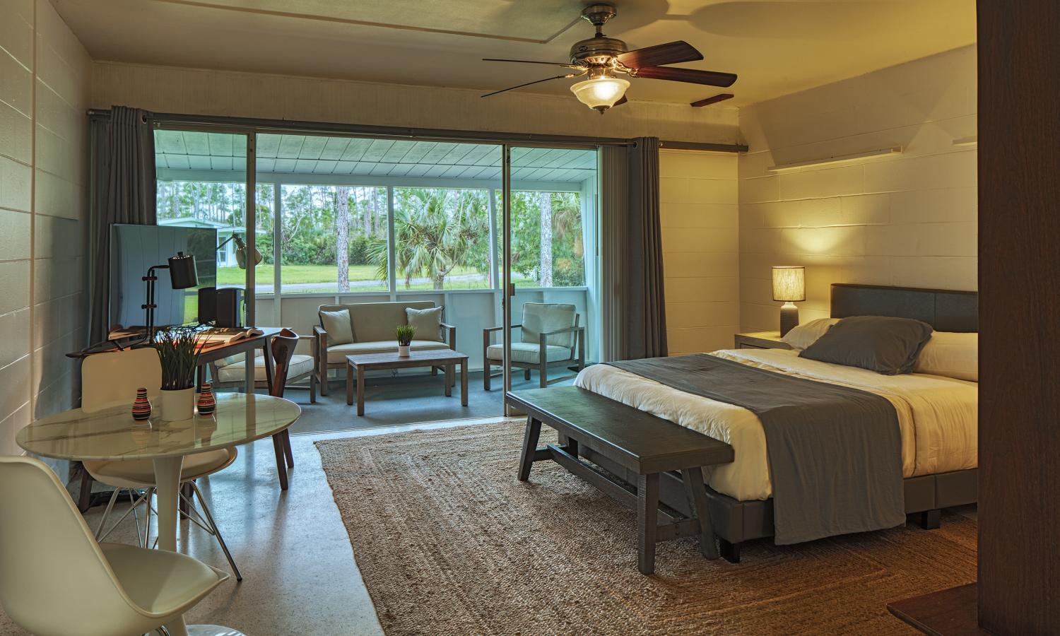 interior of the AIRIE Cabin with view of the bed, desk, dining table, and screened in porch