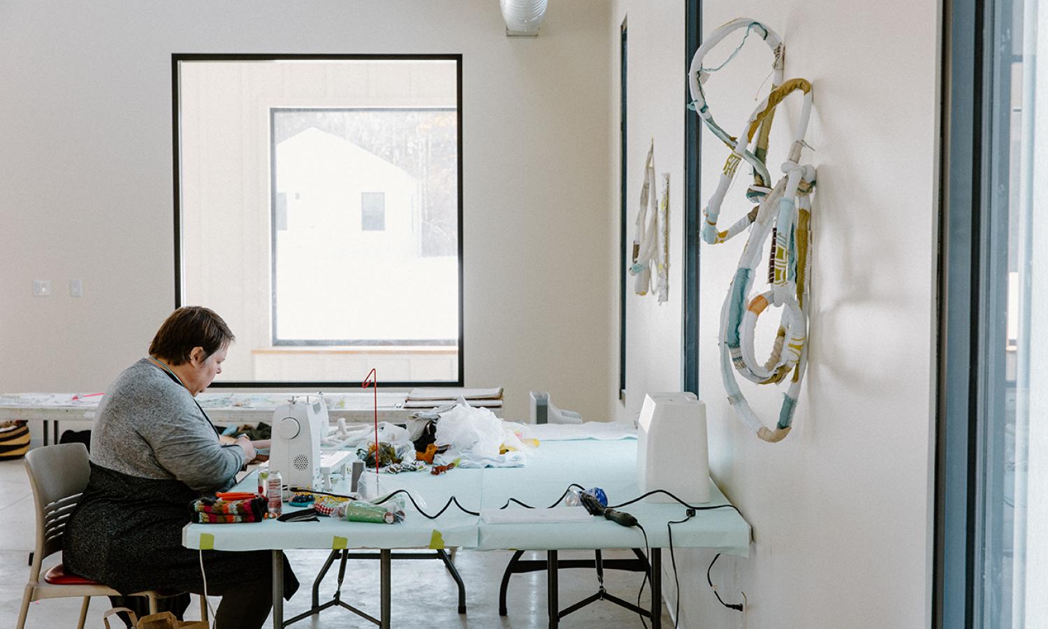 Artist-in-Residence working at sewing machine. Photo Credit: xoMe Studio