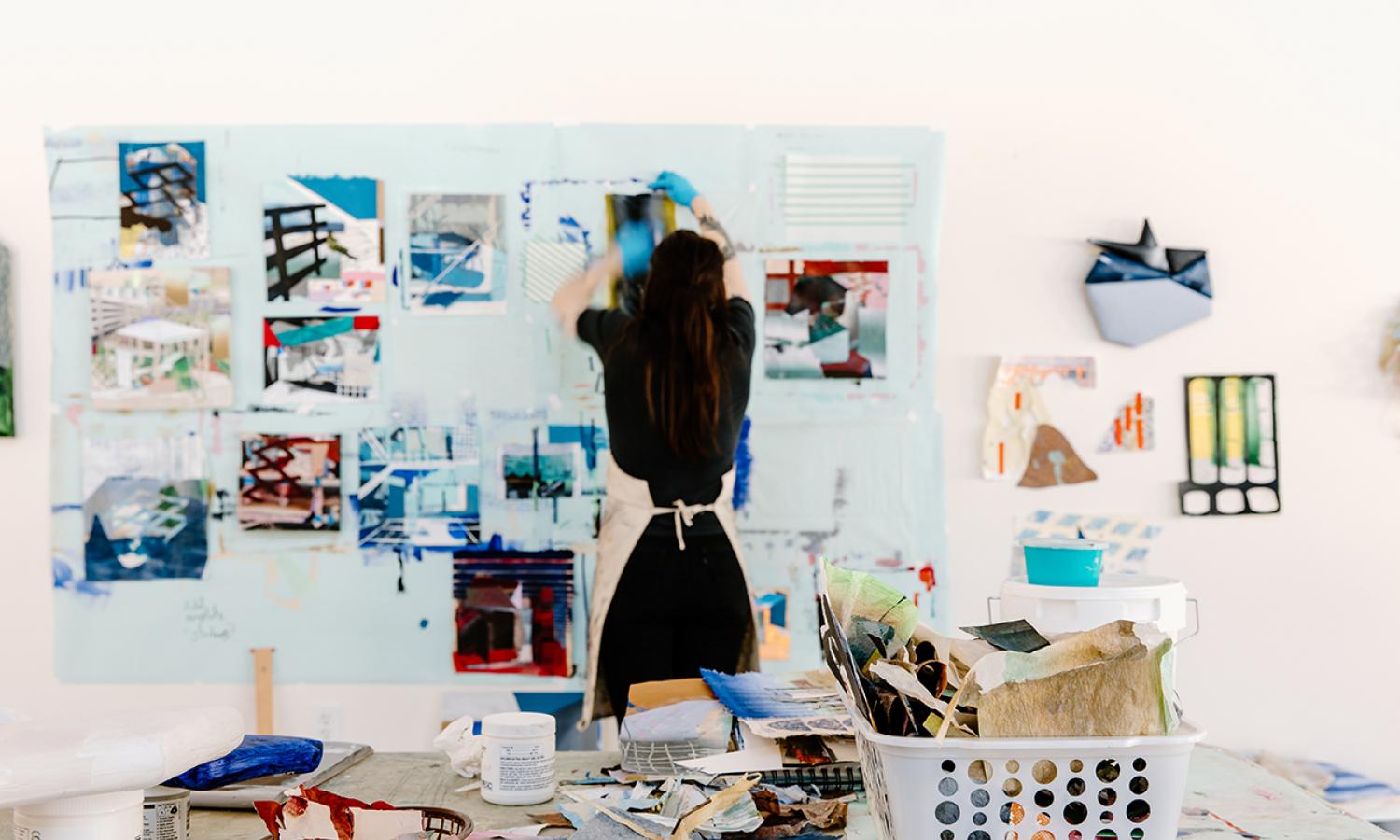 Artist-in-Residence working on variety of abstract paintings and collages on studio wall. Photo Credit: xoMe Studio