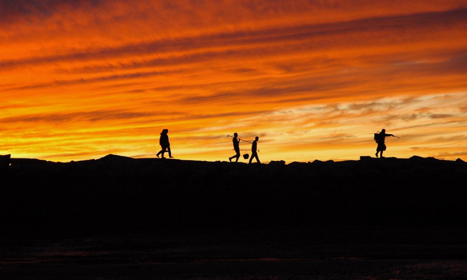 Sunset silhouette of fellows clamming at the breakwater (Proto Credit: Brian Booker)