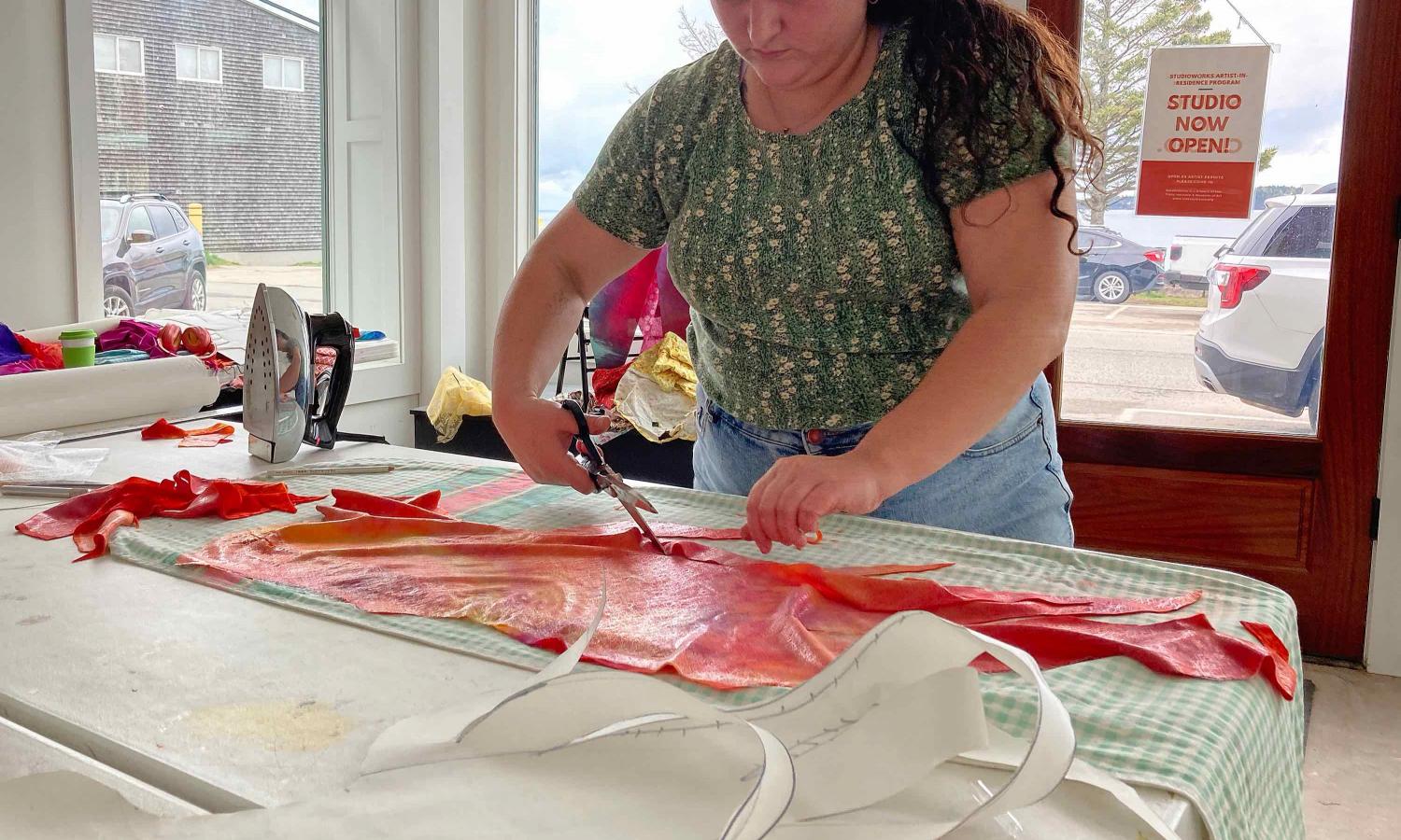 Artist Emily Oliveira cuts brightly colored fabric over-dyed in the studio to create applique quilts depicting the landscape of Passamaquoddy Bay.