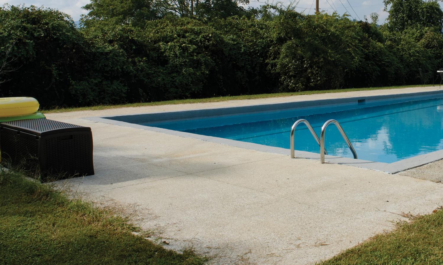 Concrete swimming pool filled with water and surrounded by nature