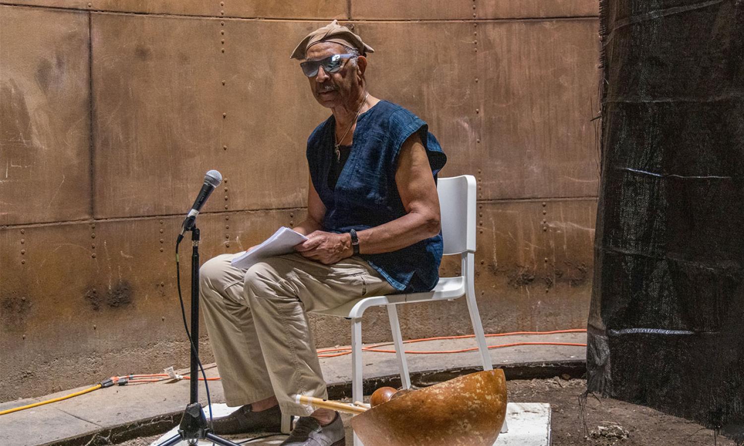 Resident seated inside a silo with a microphone and bowl of instruments