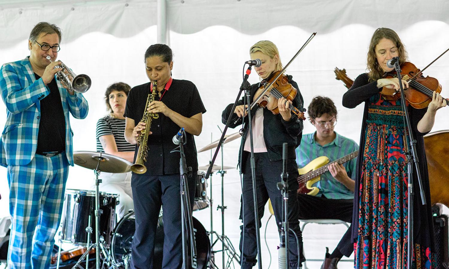 Series of musicians performing in white tent