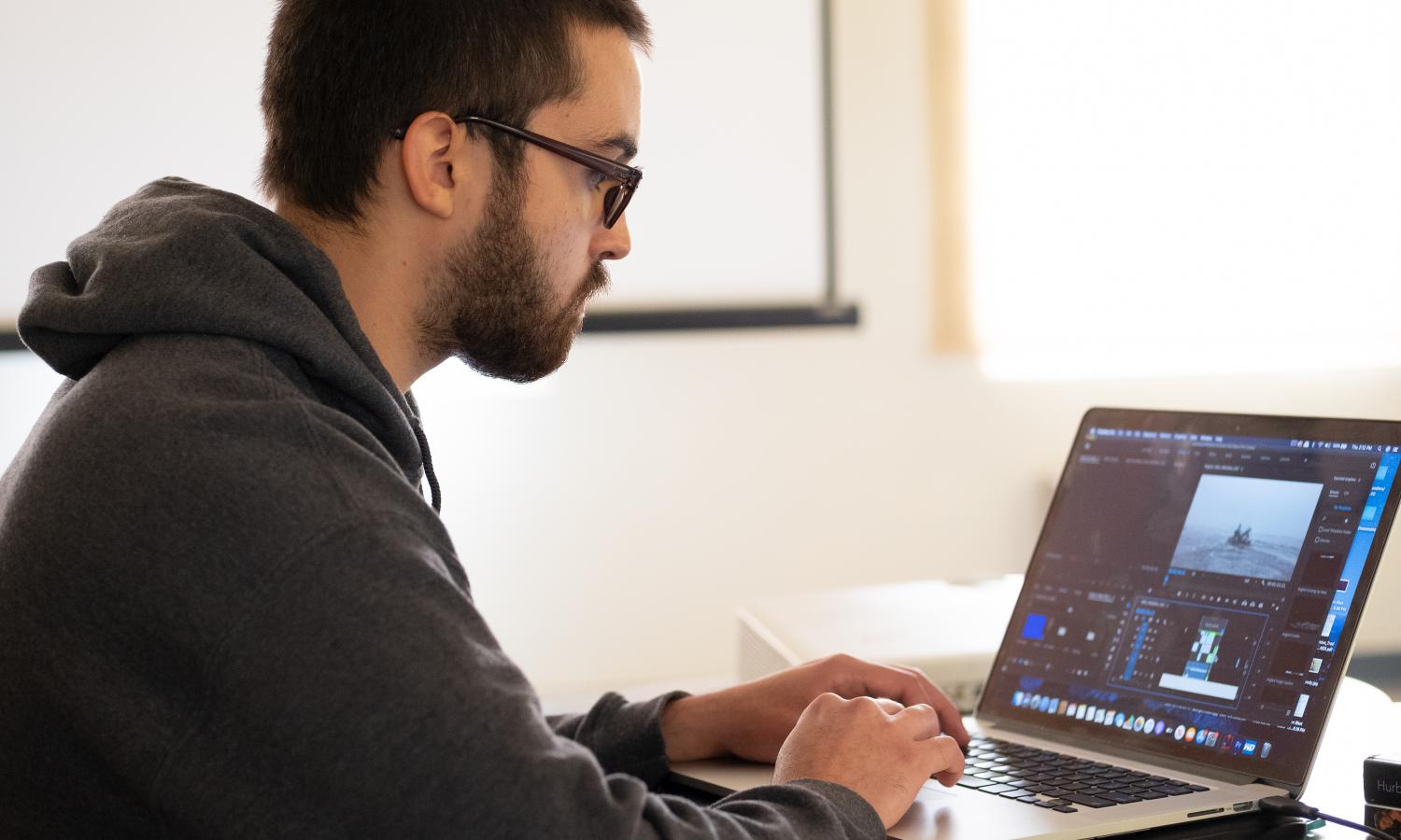 Up close photo of Woodrow Hunt working on video project on a laptop.
