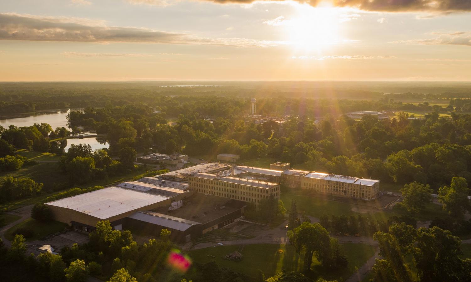 An aerial view of a paper mill surrounded by trees and lakes.