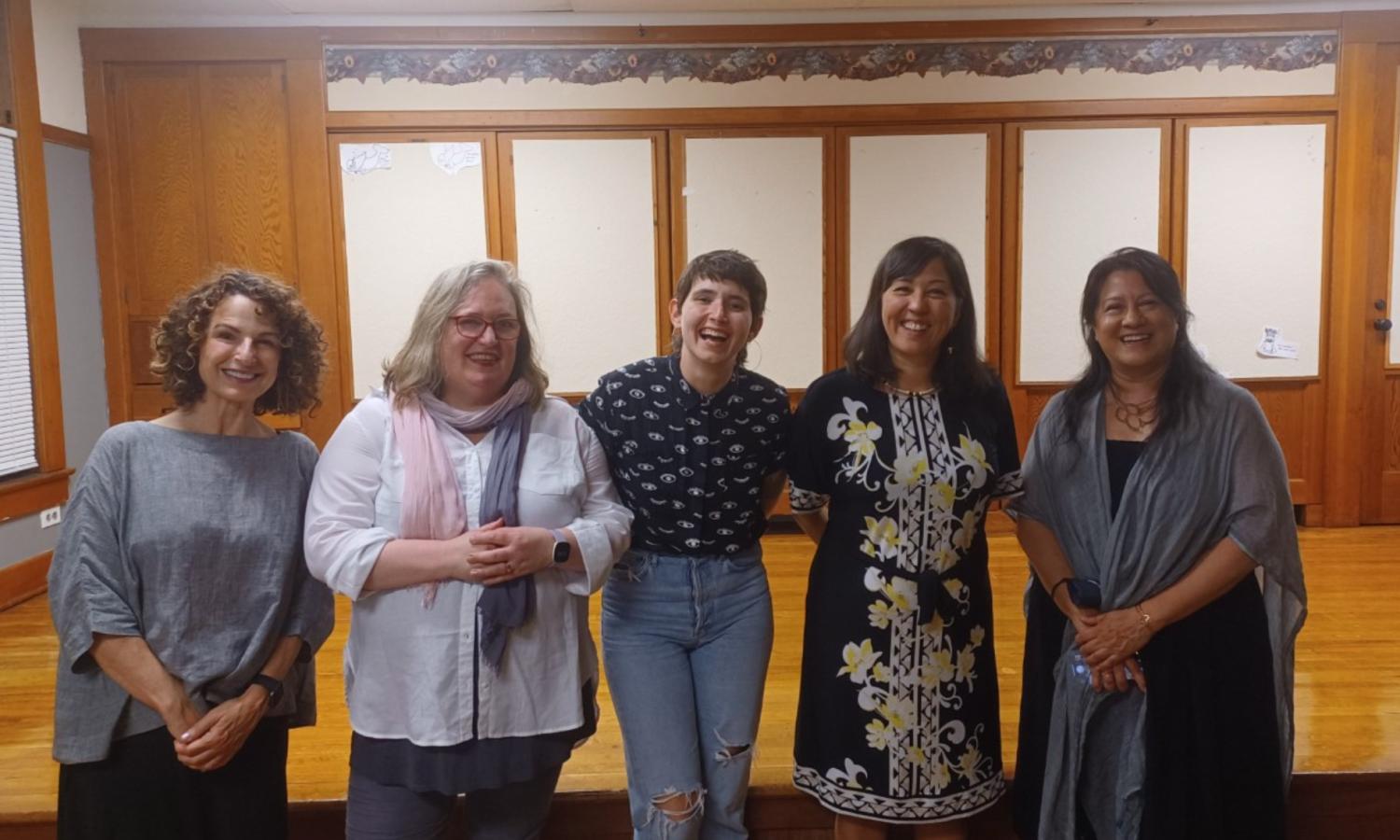 Three artist residents stand indoors in the multipurpose room with Washington State Poet Laureate Rena Priest.
