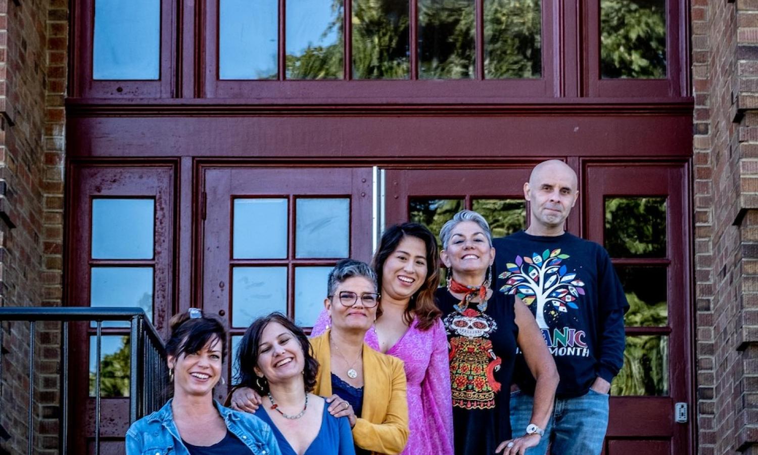 Six artists in front of the school, standing from left to right up the steps -- five women, one male on the right.