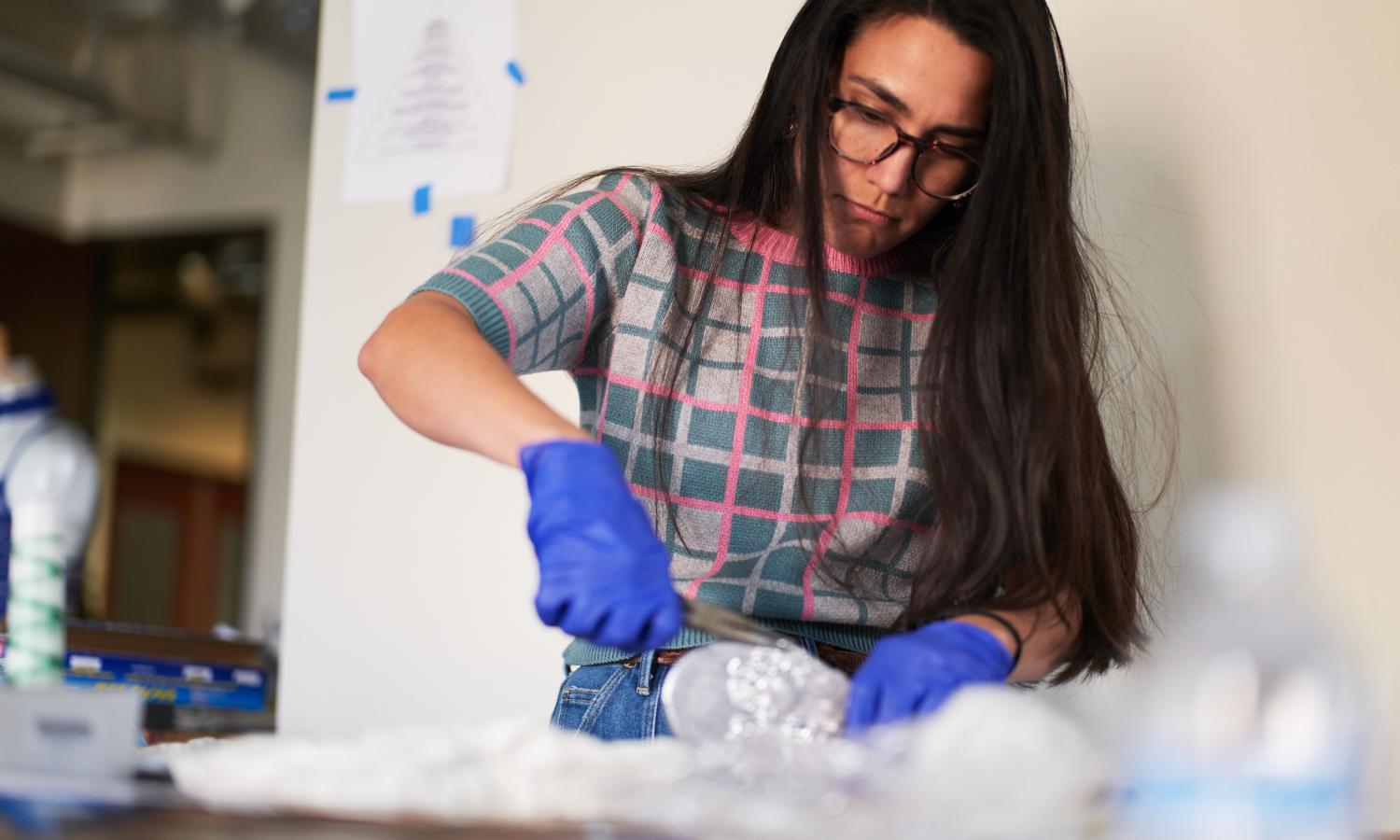 Artist Irisol Gonzalez working at a table on a mold in her studio.