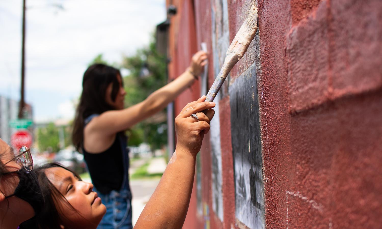 ArtLab Interns work on a wheatpaste mural