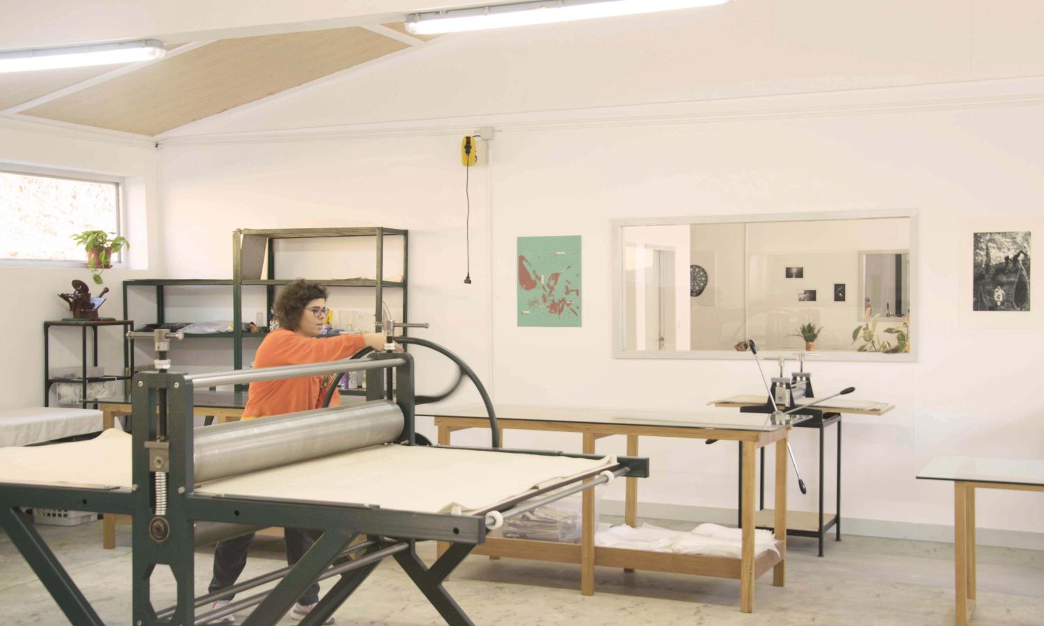 Artist printing in the large format press at the printmaking room