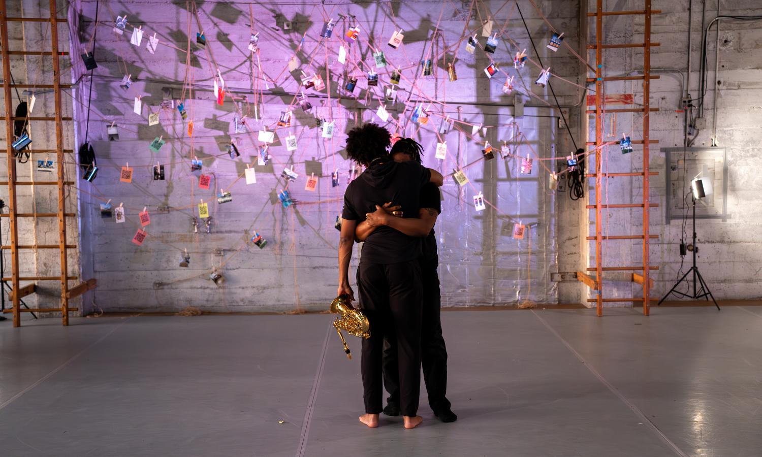 Two Black people, wearing black, embracing.