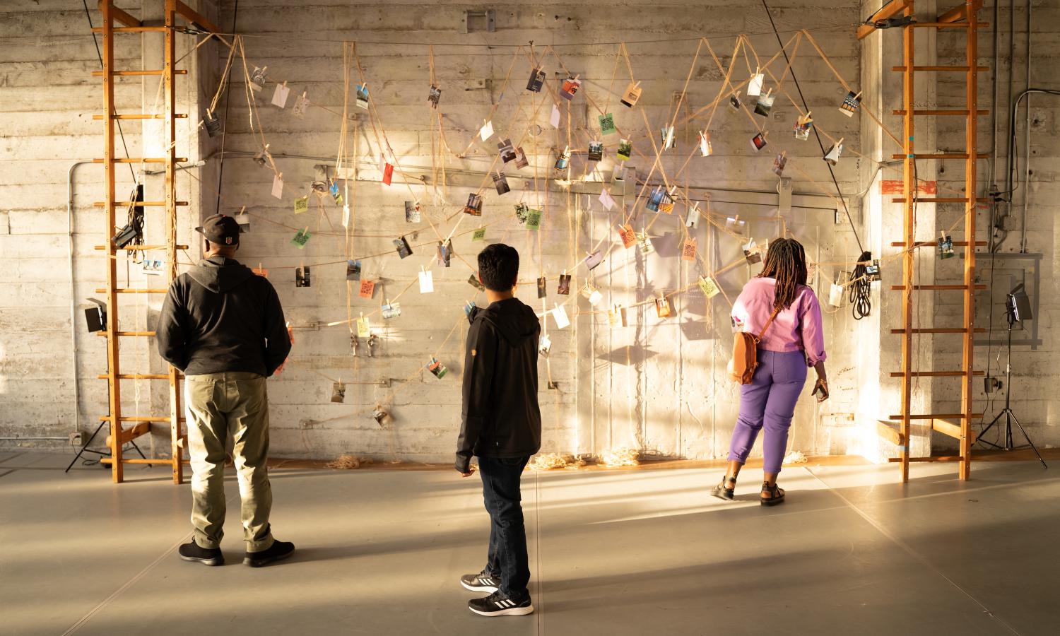 Group of people gazing at photos hung on a brick wall.