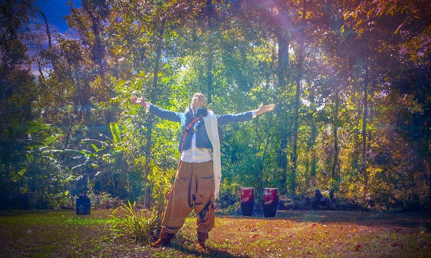 Replenish resident Kelly Love Jones in the woods with arms up