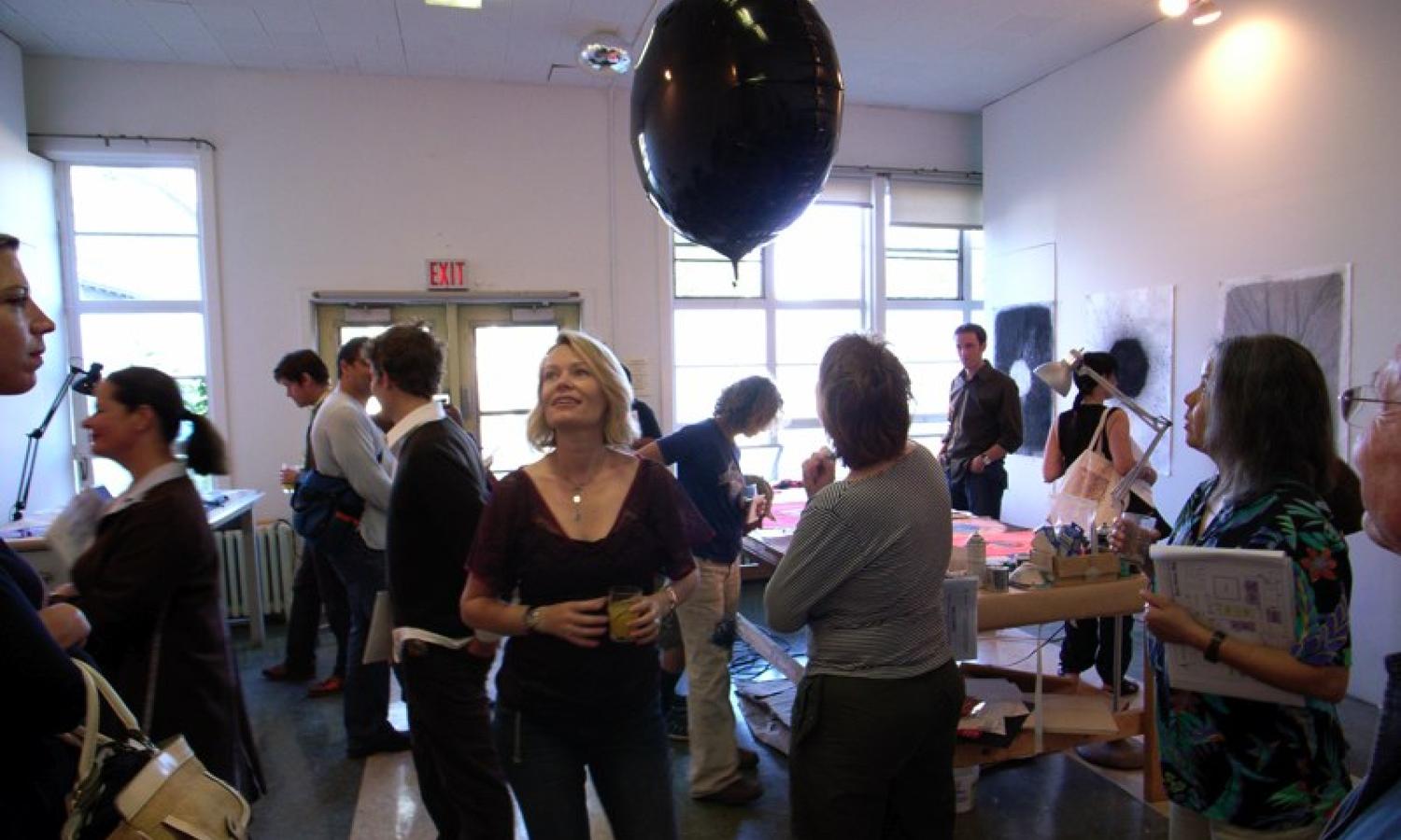 Artists gather in a large studio for a critique.