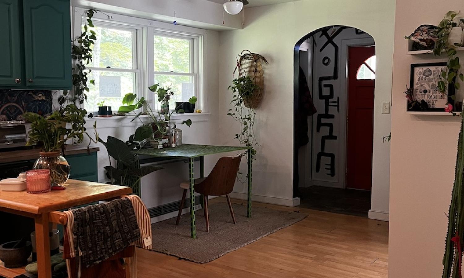A kitchen with an island, folding table, arched doorway, and many plants