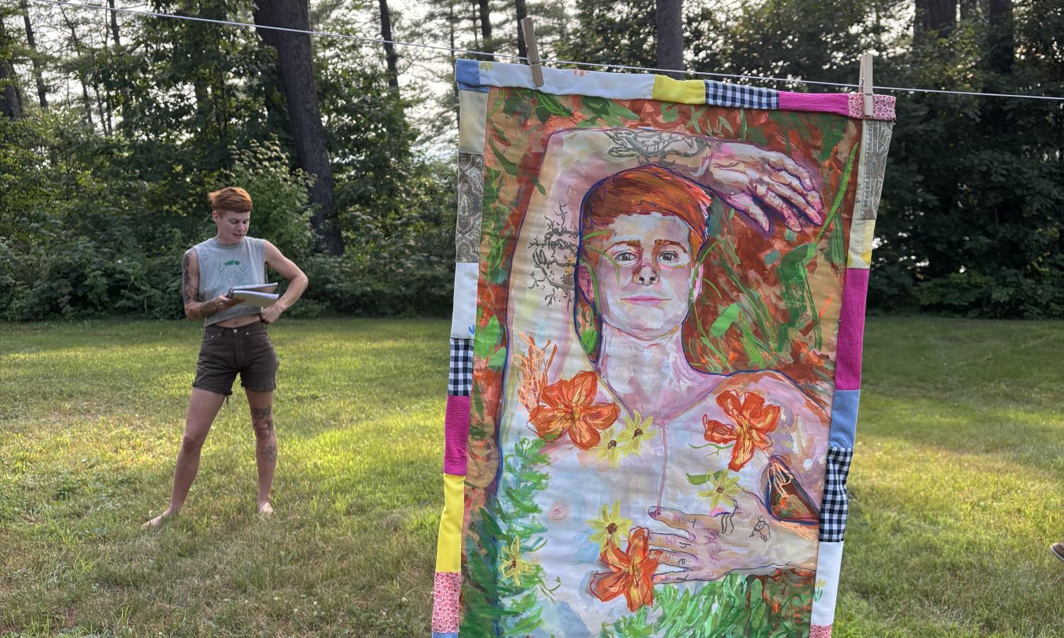 An artist looks at their quilt hanging on a cloths line