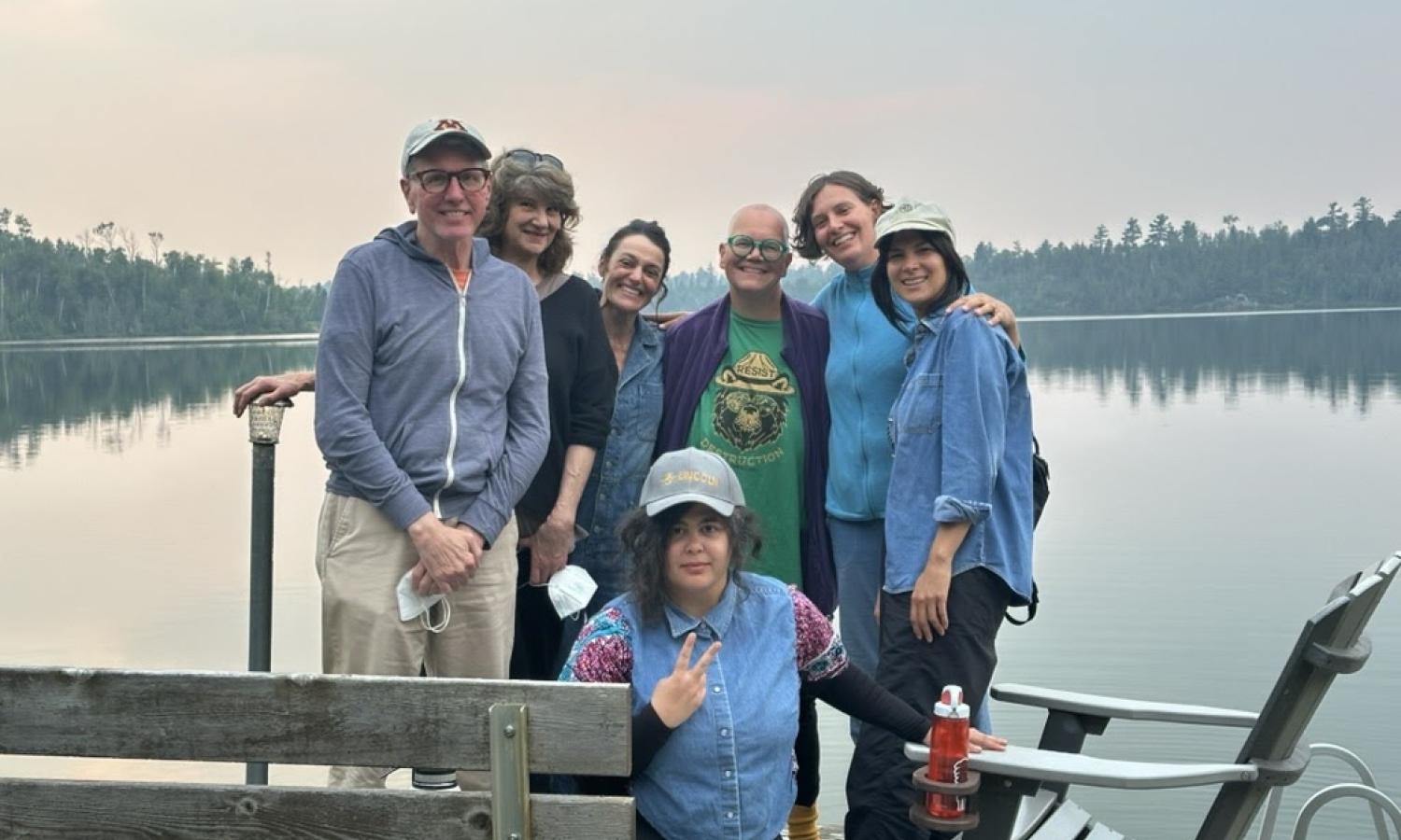Group of artists standing on a dock at a lake.