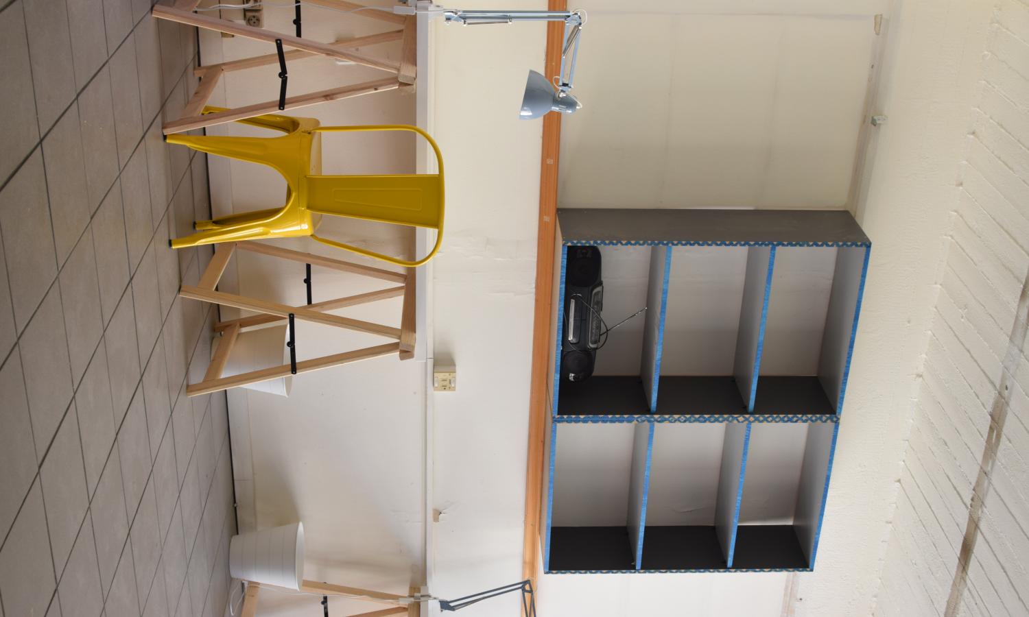 A studio setup with tables, chairs, and shelves.
