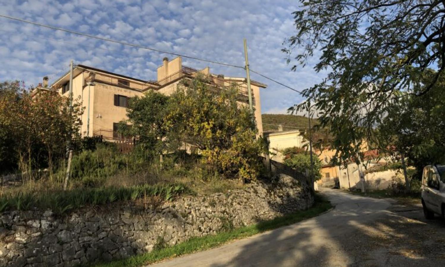 View of residency space in the village, yellow buildings surrounded by trees