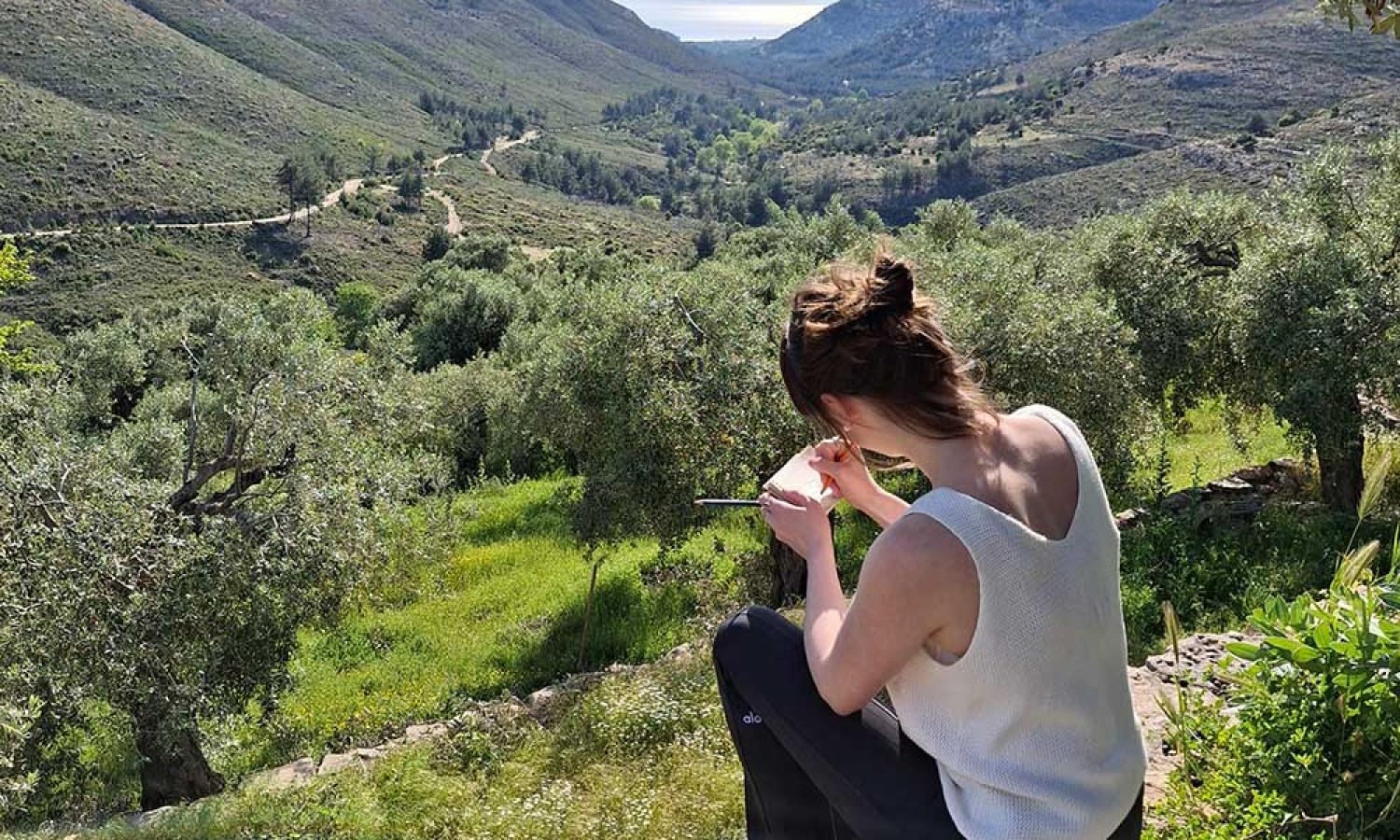 Artist Adelle Patten sketching a moutain and sea view at the Water &amp; Rock art residency in Thassos, Greece