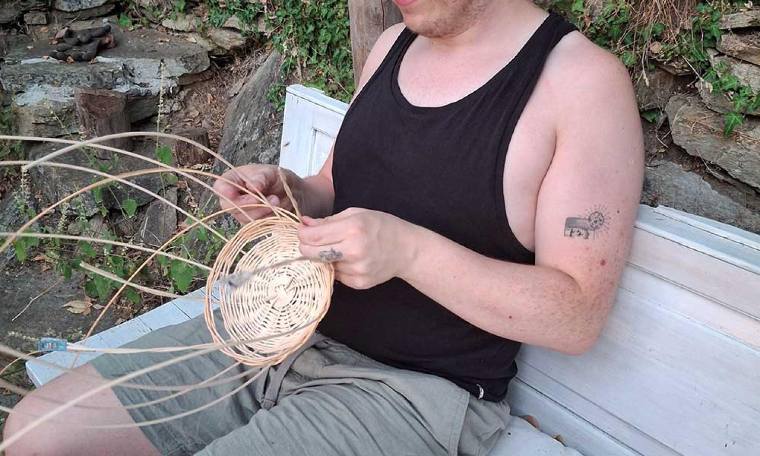 Artist Jack Pierce weaving a basket on the Water and Rock art residency terrace in Thassos, Greece