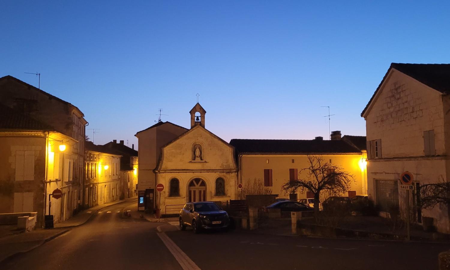 Sunset over a church and homes in the center of Mareuil-en-Perigord.