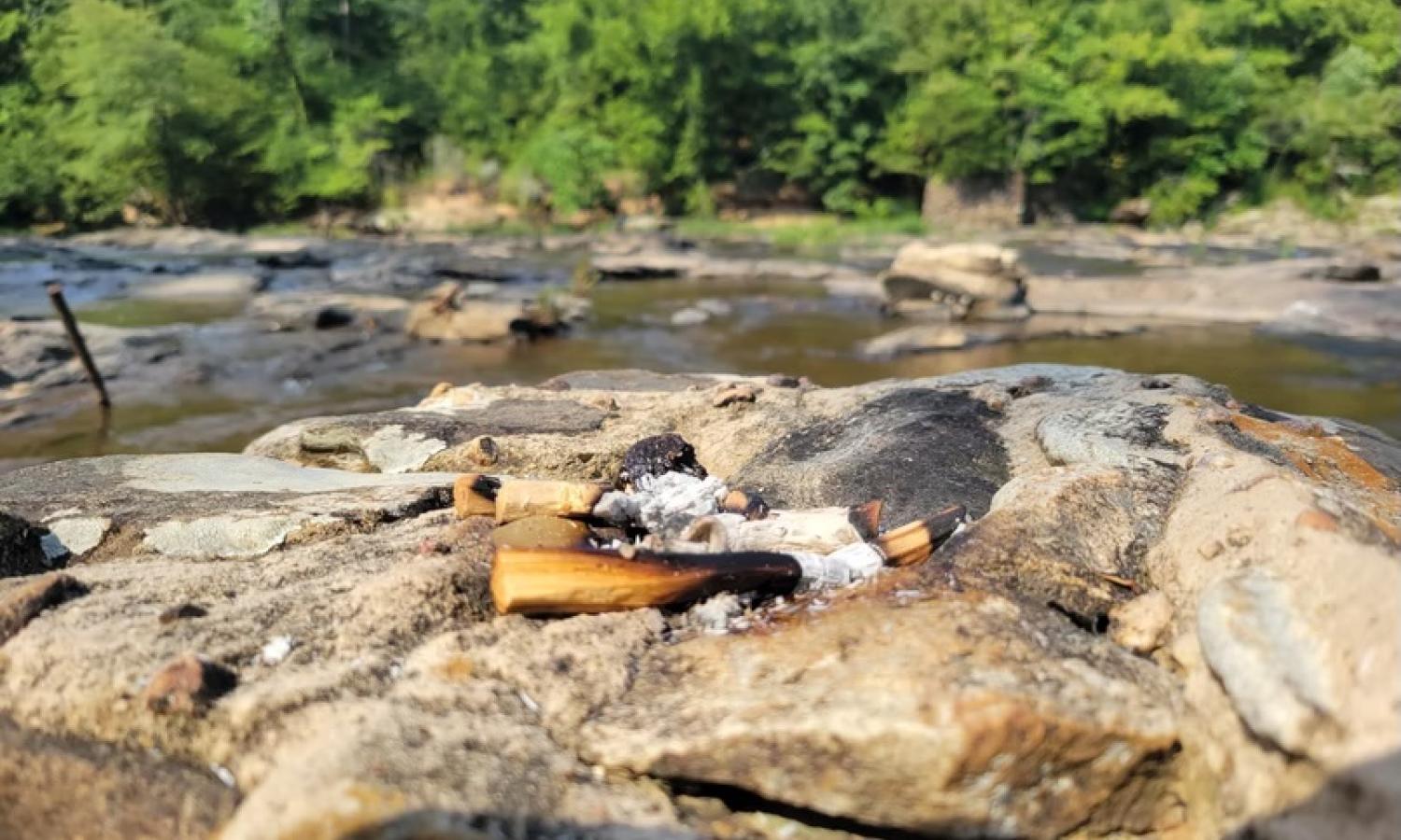 Palo Santo burning on a rock in the Great Falls River from SaltWater Road 2024 performance exploration