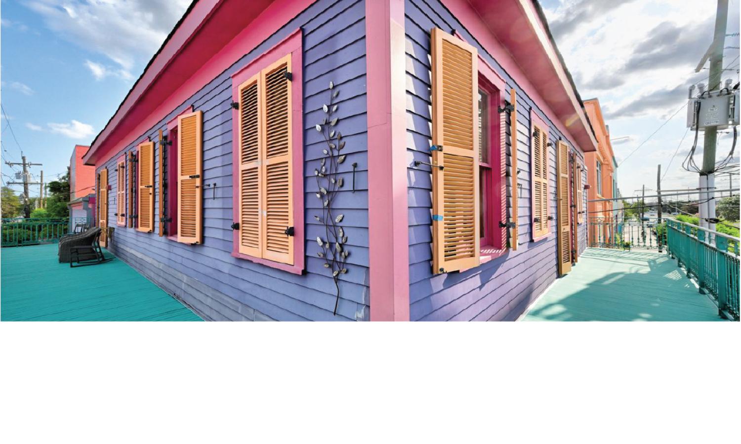 Kolaj Institute’s balcony and colorful Saint Claude Avenue facade, painted in purple, pink, and turquoise with wooden shutters.