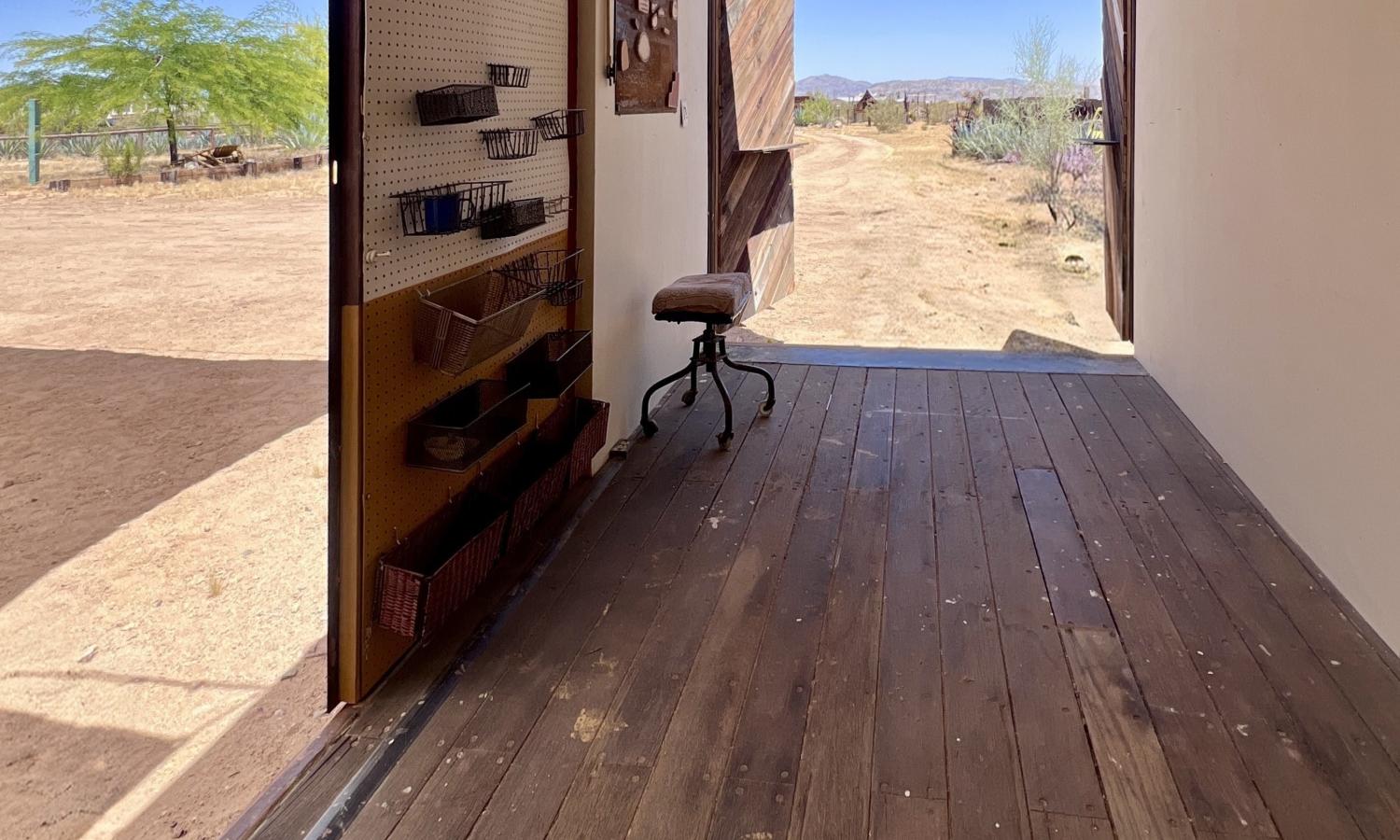 Inside of a container studio with wood floor and white walls. It has two doorways with expansive views outside.