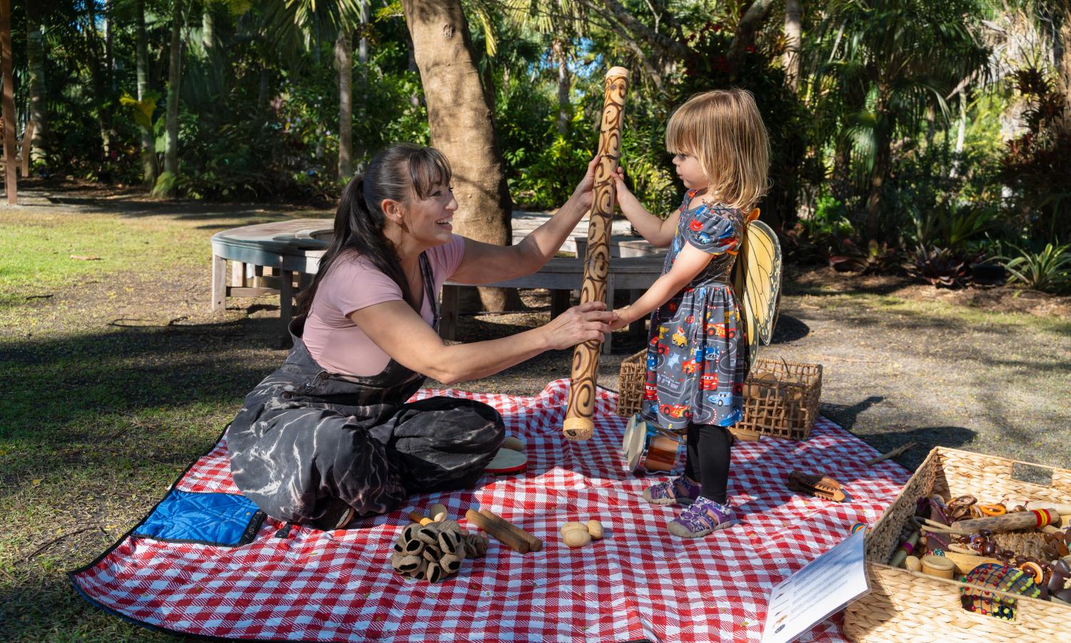 A musician is teaching a child how to use a rain stick