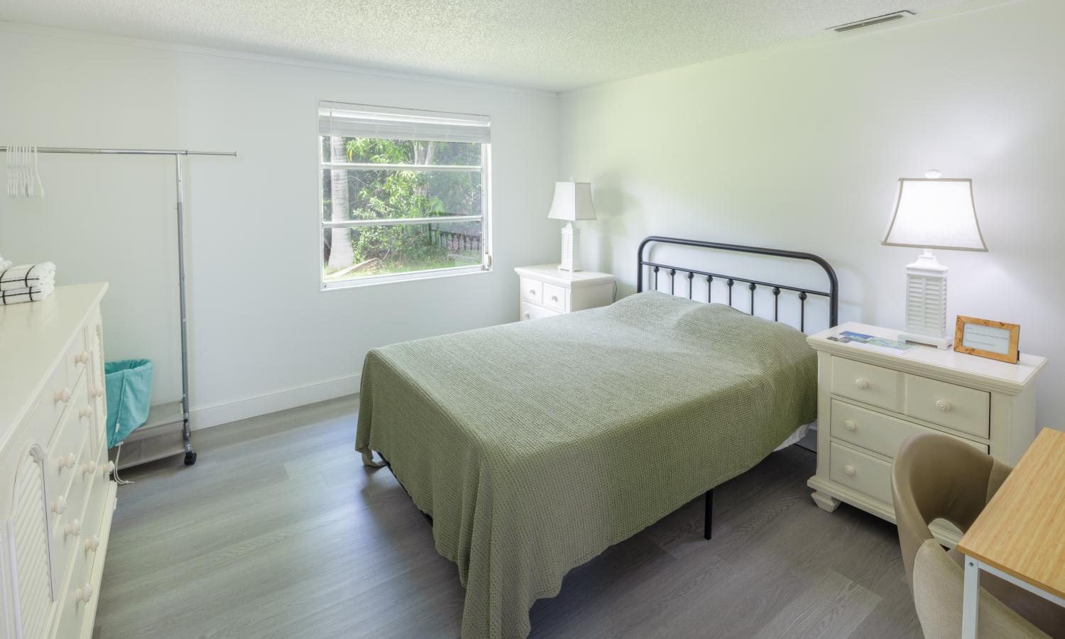 Cozy bedroom with a queen-sized bed, side tables, a desk, and dresser